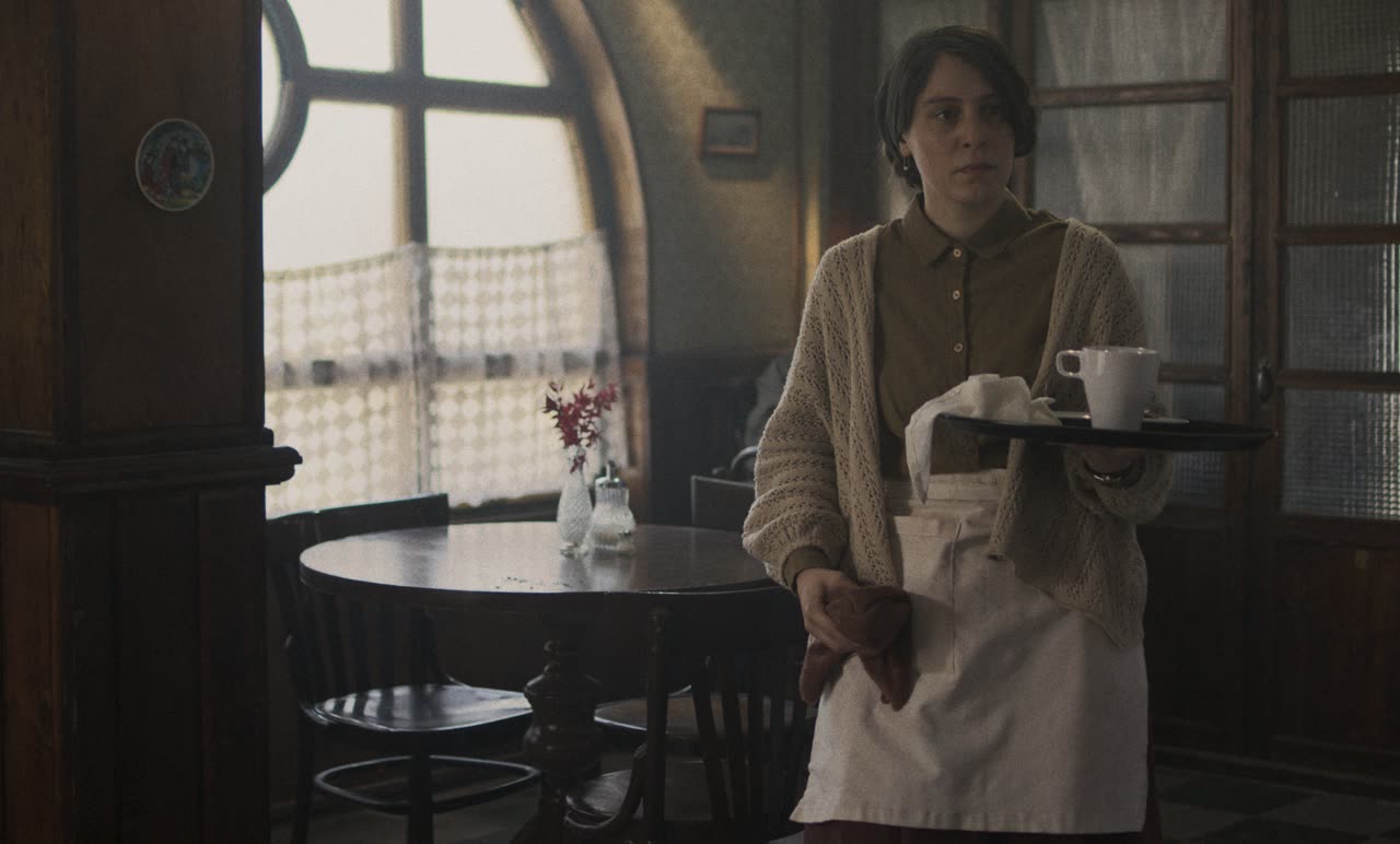 A waitress carries a tray through an empty café