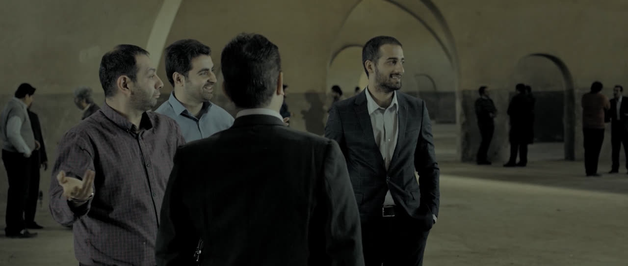 Men in suits talk in a stone courtyard