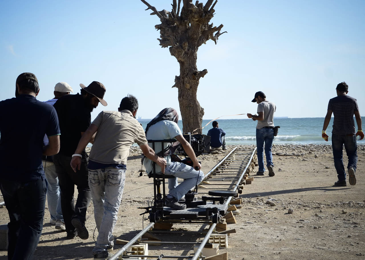 On set: the crew pushes a camera dolly along a track on the beach
