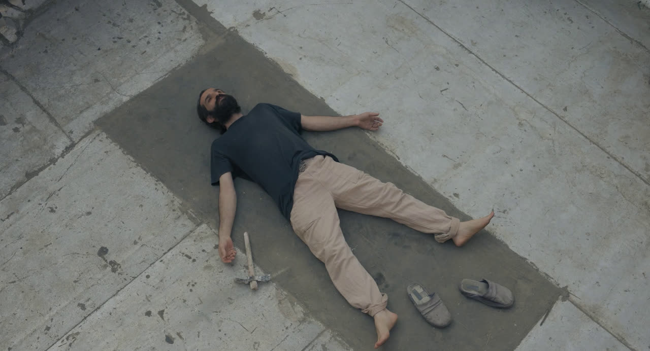 A man lies on a mat on a concrete rooftop seen from above