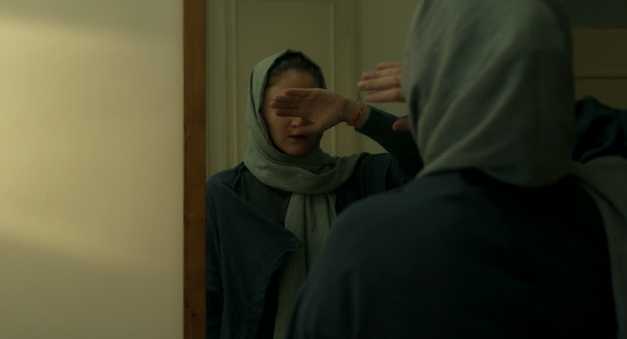 Two women in headscarves face each other in a doorway