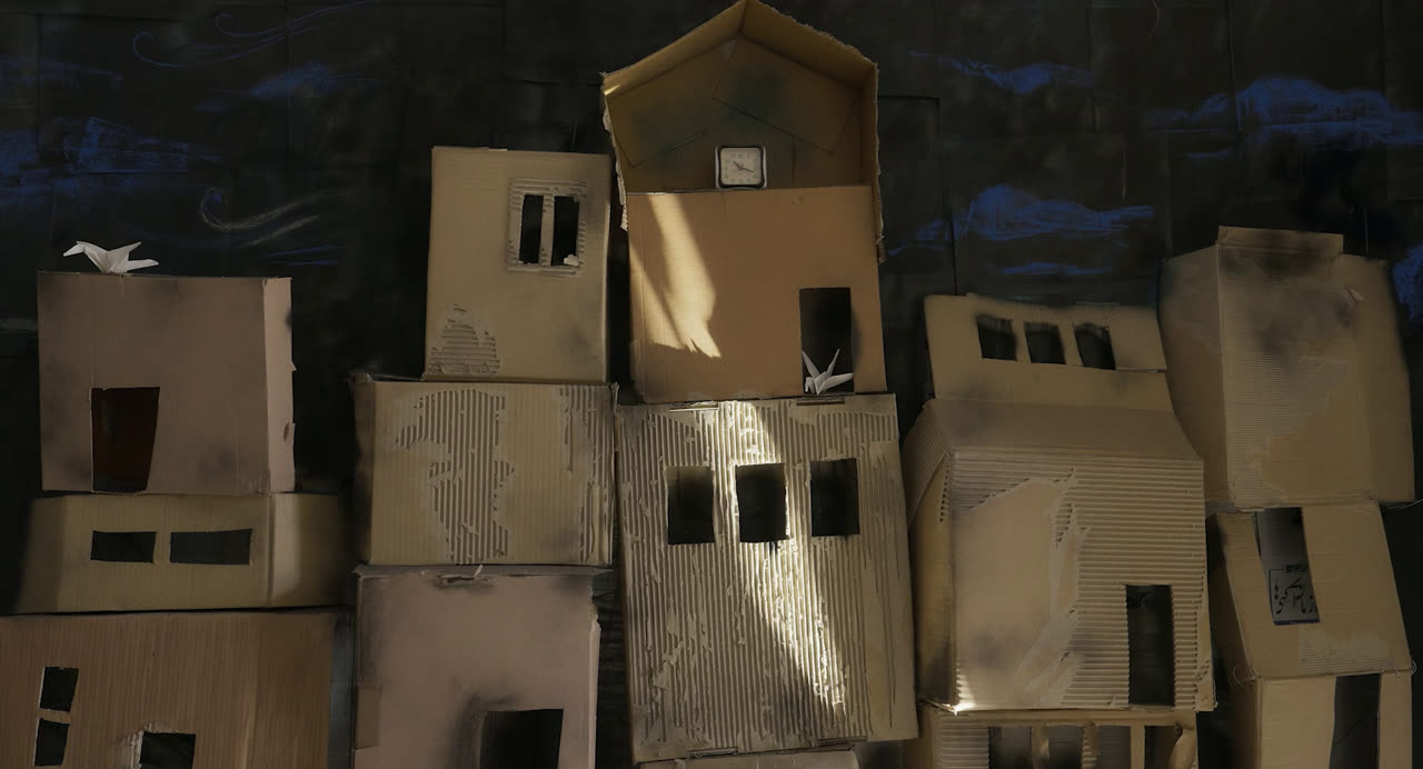 A model city of cardboard houses against a night sky